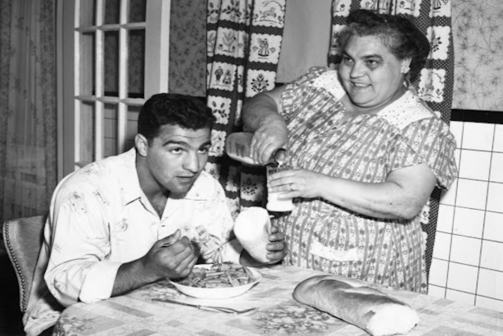 El mejor boxeador de la historia, Rocky Marciano, sentado en una mesa comiendo